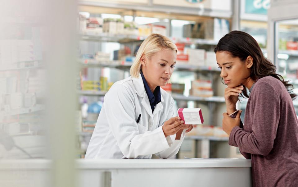 A pharmacist gives advice to a customer in a chemist