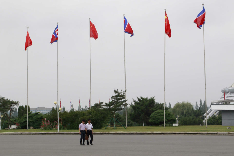 North Korean walk on a street where North Korean and Chinese national flags are hoisted in Pyongyang, North Korea Thursday, June 20, 2019. Chinese President Xi Jinping arrived Thursday morning for a two-day state visit to North Korea, where he is expected to talk with leader Kim Jong Un about the stalled negotiations with Washington over North Korea's nuclear weapons. (AP Photo/Cha Song Ho)