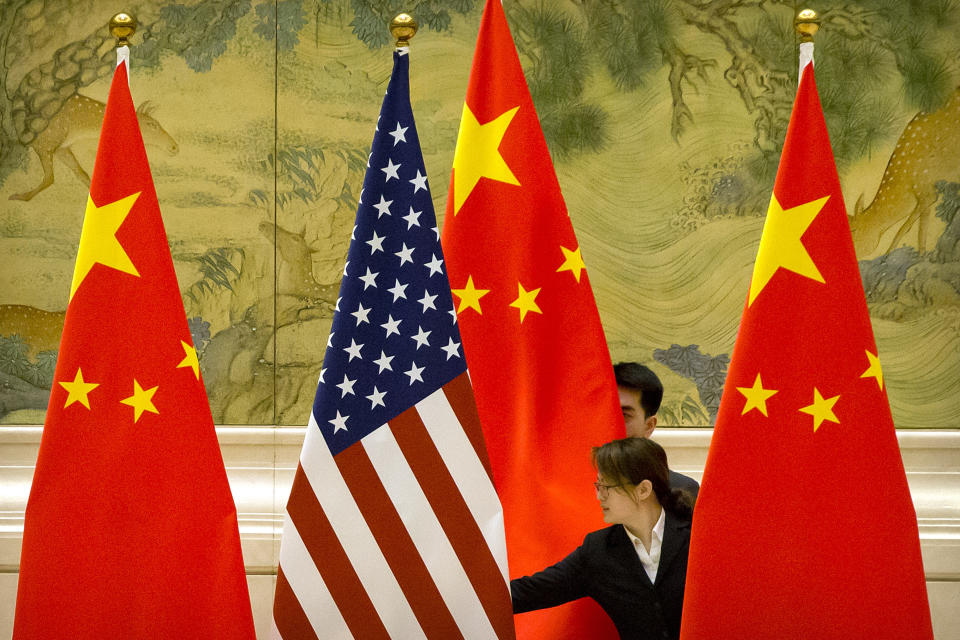 FILE - In this Feb. 14, 2019, file photo, Chinese staffers adjust U.S. and Chinese flags before the opening session of trade negotiations between U.S. and Chinese trade representatives at the Diaoyutai State Guesthouse in Beijing. Trade tensions between China and the United States are putting a drag on economies in the region, with growth likely to continue to slow in the coming two years, the Asian Development Bank says in a report released Wednesday, April 3, 2019. (AP Photo/Mark Schiefelbein, File)