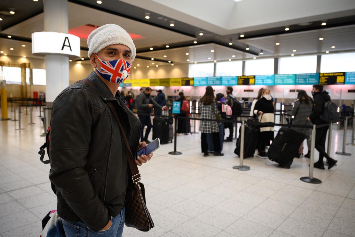 <p>A passenger wearing a Union Flag face mask waits in the North Terminal to board one of the few flights departing at Gatwick Airport </p> (Getty)