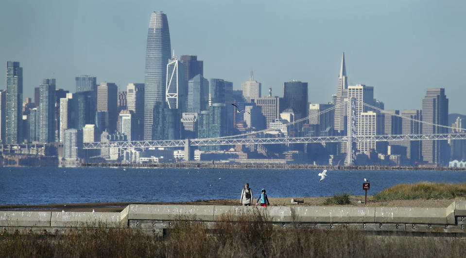 Birdwatchers wear jackets at the Elsie Roemer Bird Sanctuary on Wednesday, Jan. 2, 2019, in Alameda, Calif. San Francisco skyline is seen in background. Snow is falling on cacti in southern Arizona, while Anchorage is seeing balmy weather - at least by Alaska standards. The weather appears to be flipped throughout much of the West. (AP Photo/Ben Margot)