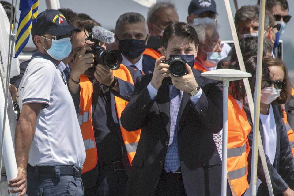 Italian Premier Giuseppe Conte takes photos from aboard a Coast Guard ship in Venice, Italy, Friday, July 10, 2020. Venice has conducted a trial run an ambitious anti-flood system of 78 inflatable barriers in the hopes of protecting the lagoon city from devastating high tides. Premier Giuseppe Conte on Friday at a ceremony in Venice pressed a button that activated compressors to pump air into the bright yellow barriers, which then started rising from the sea to act a kind of a dike-on-demand. (Claudio Furlan/LaPresse via AP)