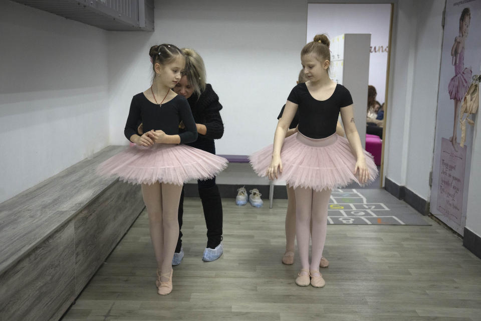 Mother and teacher prepare the girls to practice in a ballet studio in a bomb shelter in Kharkiv, Ukraine, Monday, March 18, 2024. In northeast Ukraine, a dance studio that doubles as a bomb shelter is an escape from the horrors of war for about 20 young girls. The Princess Ballet Studio in Kharkiv is a spartan, windowless room, but practicing underground means they can dance through the almost hourly air raid alerts. (AP Photo/Efrem Lukatsky)