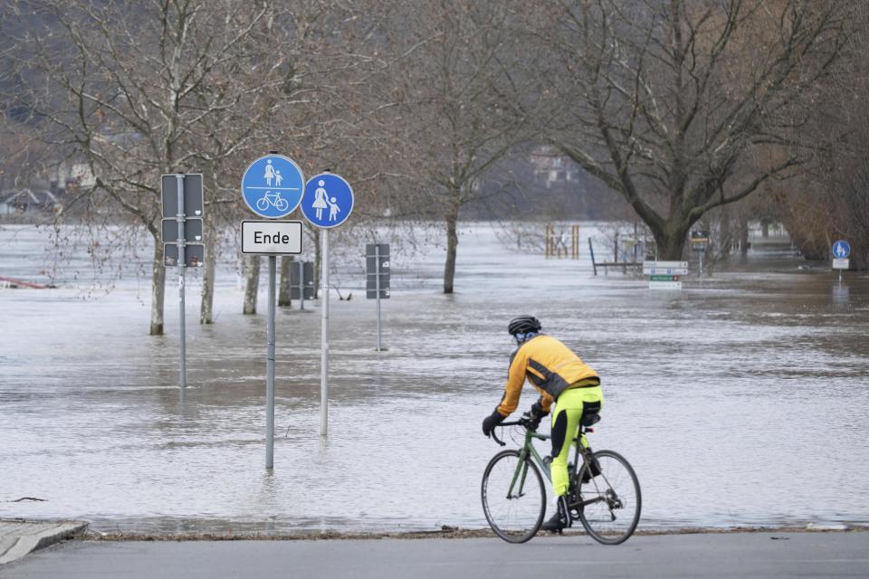 A cyclist drives on a road next to an area flooded by the river Elbe, in Pirna, Germany, Thursday Dec. 28, 2023. (Sebastian Kahnert/dpa via AP)