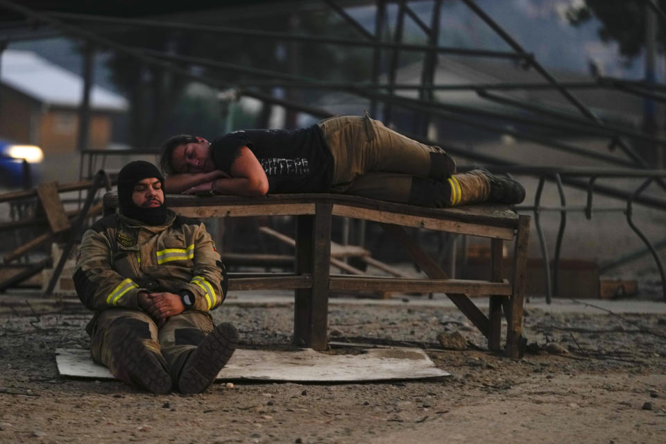 Dos bomberos se toman un descanso en las labores de extinción de un incendio forestal en Viña del Mar, Chile, el 3 de febrero de 2024. (AP Foto/Esteban Félix)