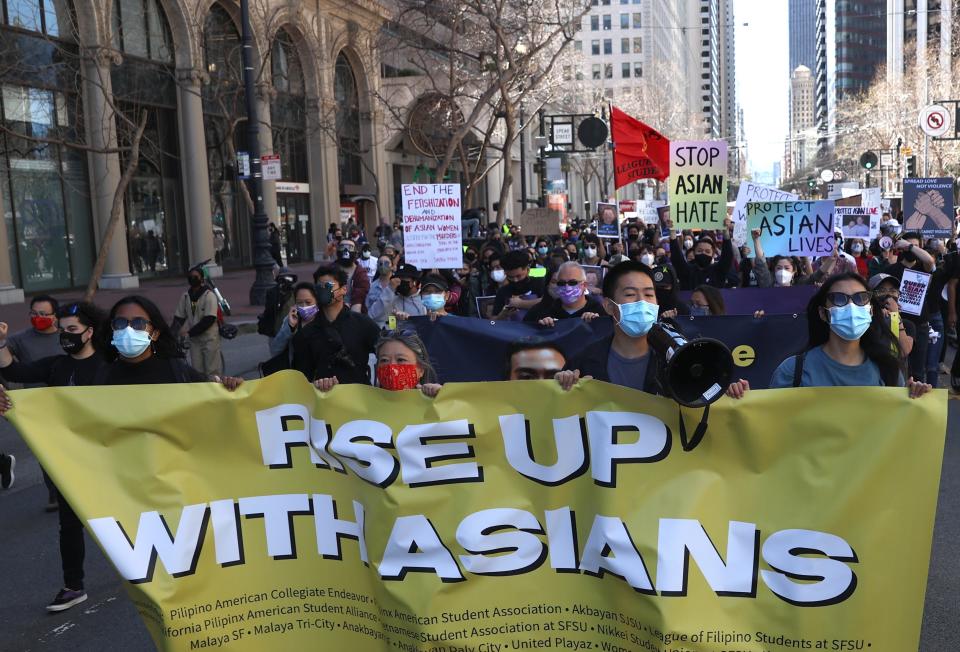 Protesters hold signs as they march along Market Street before a rally to show solidarity with Asian Americans at Embarcadero Plaza on March 26, 2021, in San Francisco. Hundreds of people marched through downtown San Francisco and held a rally at Embarcadero Plaza in solidarity with Asian Americans who have recently been the targets of hate crimes across the United States.
