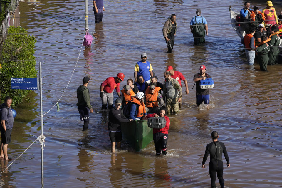People evacuate an area flooded by heavy rains in Porto Alegre, Rio Grande do Sul state, Brazil, Thursday, May 9, 2024. (AP Photo/Andre Penner)
