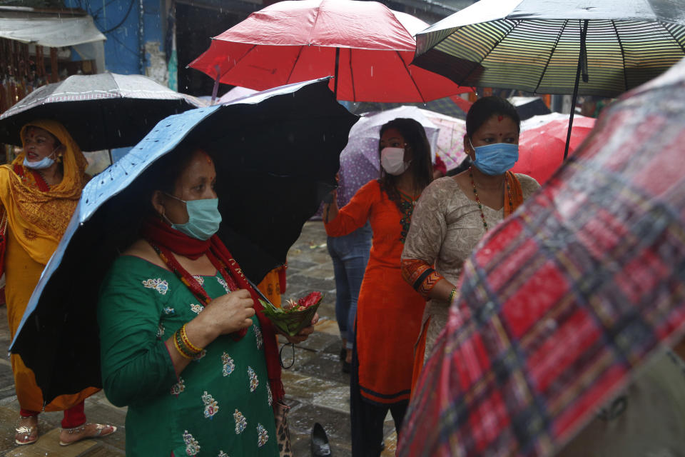 Nepalese Hindu devotees wearing masks offer prayers from outside the closed gate of Pashupatinath temple during the holy month of Shrawan in Kathmandu, Nepal, Monday, July 20, 2020. The temple has been remaining closed for almost four months as part of measures to control the spread of the coronavirus. (AP Photo/NIranjan Shrestha)