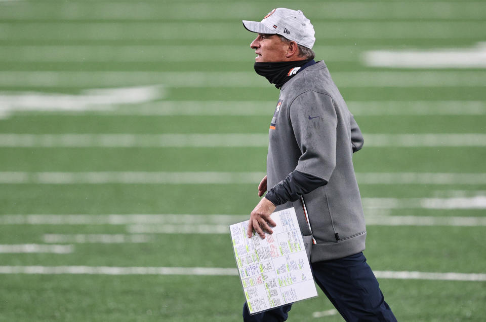 Vic Fangio with the play sheet in hand walks across an empty field.