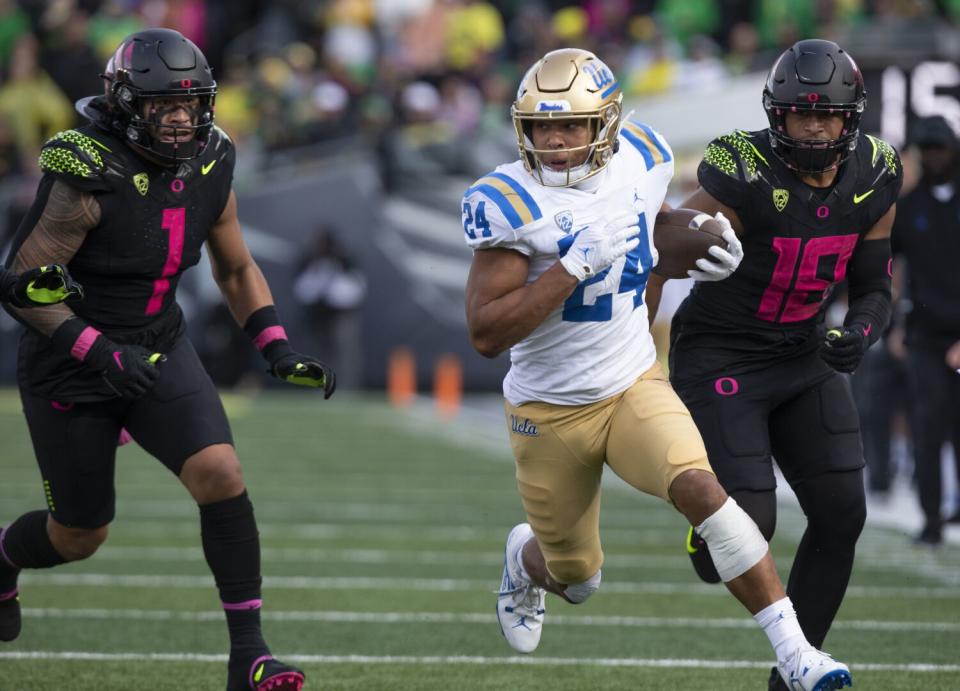 UCLA's Zach Charbonnet outruns Oregon's Noah Sewell and Mase Funa.