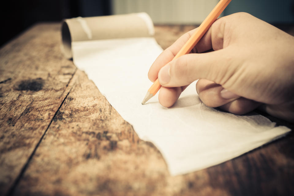 Eine Hand schreibt auf Klopapier (Symbolbild: Getty Images)