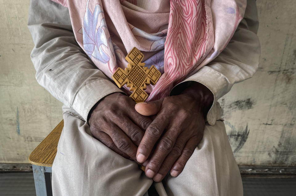 A priest, who did not wish to be identified, and said he was captured after trying to flee recent conflict and put in prison for two months and his best friend shot on the journey, sits with his Ethiopian Orthodox cross after arriving at a makeshift camp for displaced people in Shire, in the Tigray region of northern Ethiopia Wednesday, Feb. 24, 2021. For months, one great unknown in Ethiopia's Tigray conflict has been the fate of hundreds of thousands of people in vast rural areas beyond the reach of outside aid, but now thousands who have been hiding there have begun arriving in a community that can barely support them. (Third Party via AP)