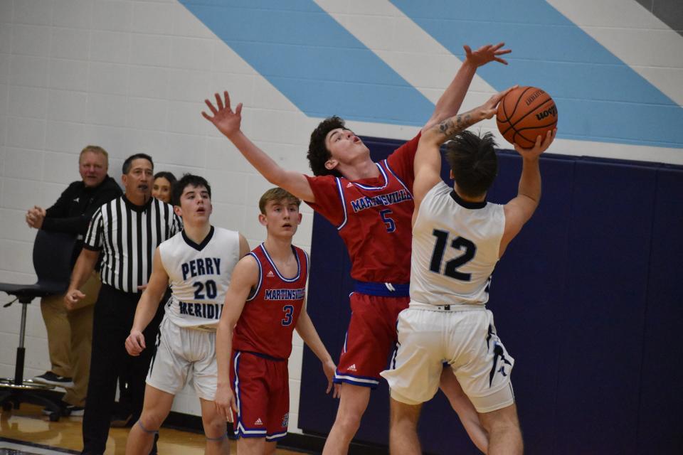 Martinsville senior Landon Myers absorbs contact mid-air as Perry Meridian guard Izaiah Brinker goes for a layup during their game on Jan. 21, 2022.