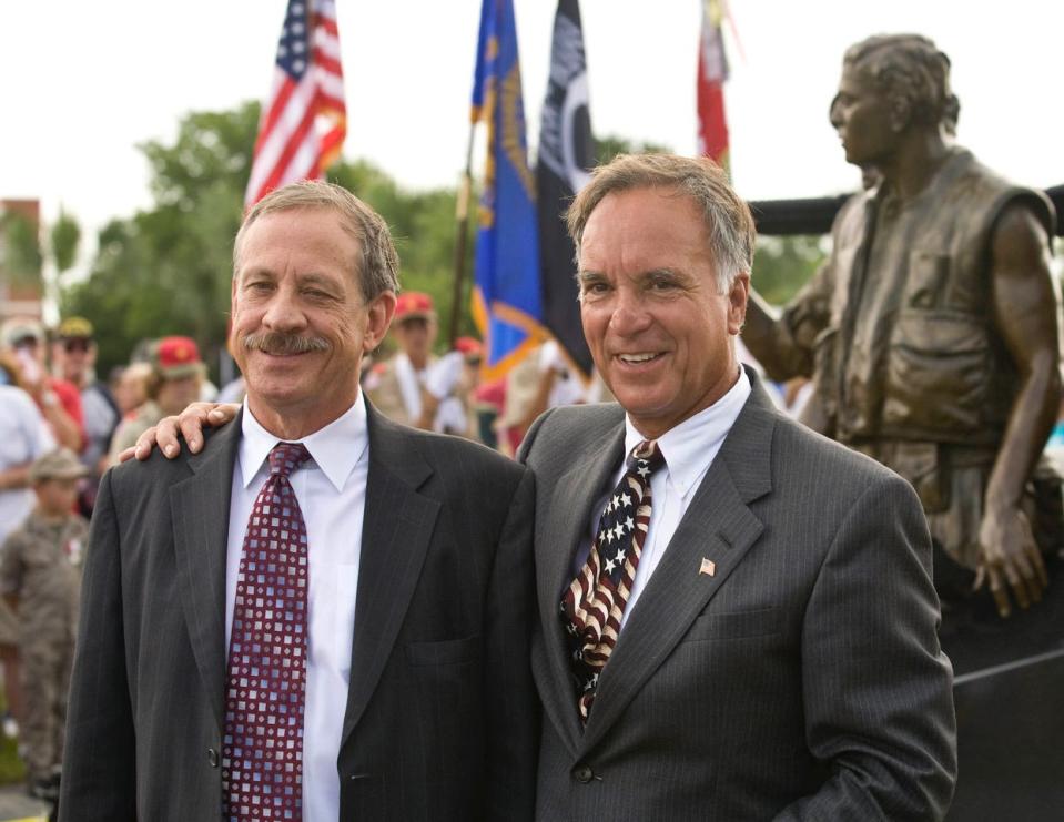 Vietnam War veterans Jan Scruggs, left, and Jimmy Mosconis pose together at an event in Apalachicola in 2008. A replica of the Three Servicemen bronze statue stands behind them at right.