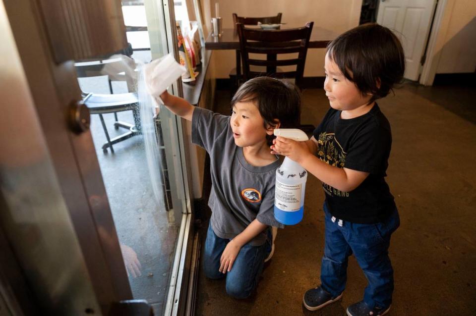 Toki Sawada’s sons, Haru Takehara, 5, and Yoshi Takehara, 3, help out their mom at the restaurant by cleaning the glass door Wednesday.