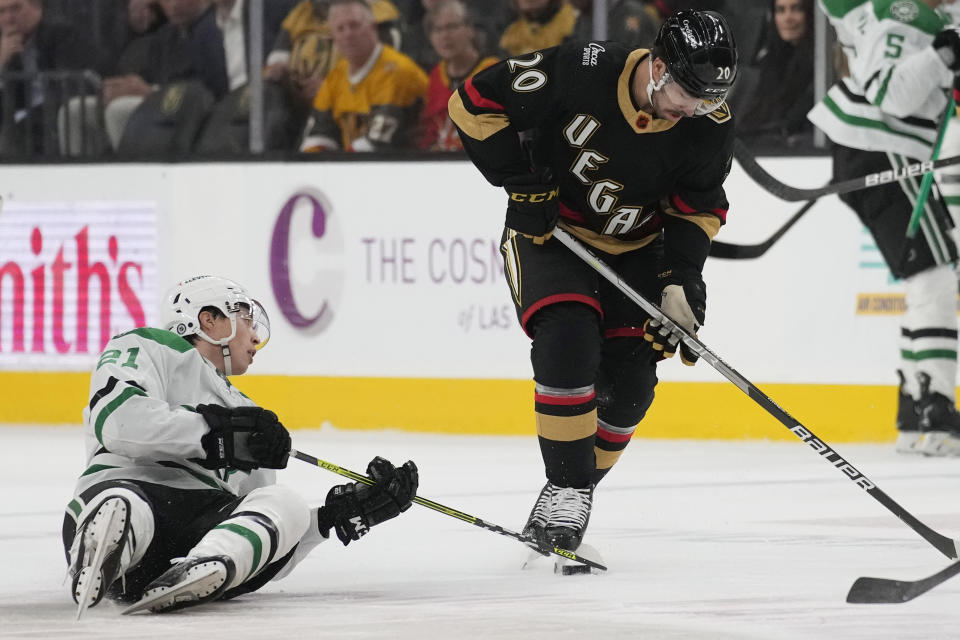 Dallas Stars left wing Jason Robertson (21) and Vegas Golden Knights center Chandler Stephenson (20) battle for the puck during the first period of an NHL hockey game Monday, Jan. 16, 2023, in Las Vegas. (AP Photo/John Locher)