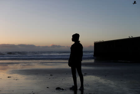 FILE PHOTO: Bessi Quintanilla, a migrant from Honduras, part of a caravan of thousands traveling from Central America en route to the United States, poses in front of the border wall between the U.S. and Mexico in Tijuana, Mexico, November 24, 2018. REUTERS/Kim Kyung-Hoon