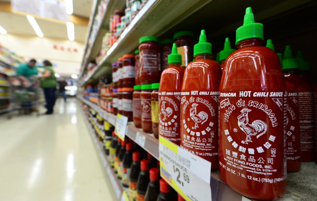 Bottles of Sriracha chili sauce are displayed on shelves as people shop inside a supermarket in Rosemead, California, on October 31, 2013. A Los Angeles Superior Court judge refused to halt operations of Sriracha's chili sauce plant in Irwindale, California, due to complaints from neighbors about the sting in the air when the peppers are mashed. A November 22 hearing has been scheduled on whether to issue a preliminary injunction after the city of Irwindale sued the sauce-maker Huy Fong Foods Inc., on October 28 claiming it a public nuisance. The Rosemead-based company, founded by Vietnamese immigrant David Tran in 1980 in Los Angeles Chinatown, uses fresh chili's which are mashed during a two-month autumn period. AFP PHOTO/Frederic J. BROWN (Photo credit should read FREDERIC J. BROWN/AFP via Getty Images)