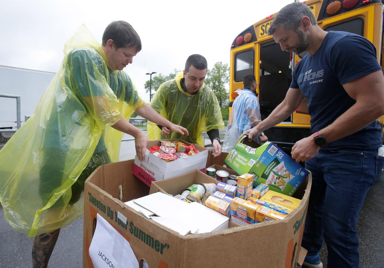 Volunteers from Surgere, from left, Jack Burton, Ian Lab and Steve Smolinski unload food items Monday from a Jackson Local school bus at the Akron-Canton Foodbank's Stark Campus in Canton.