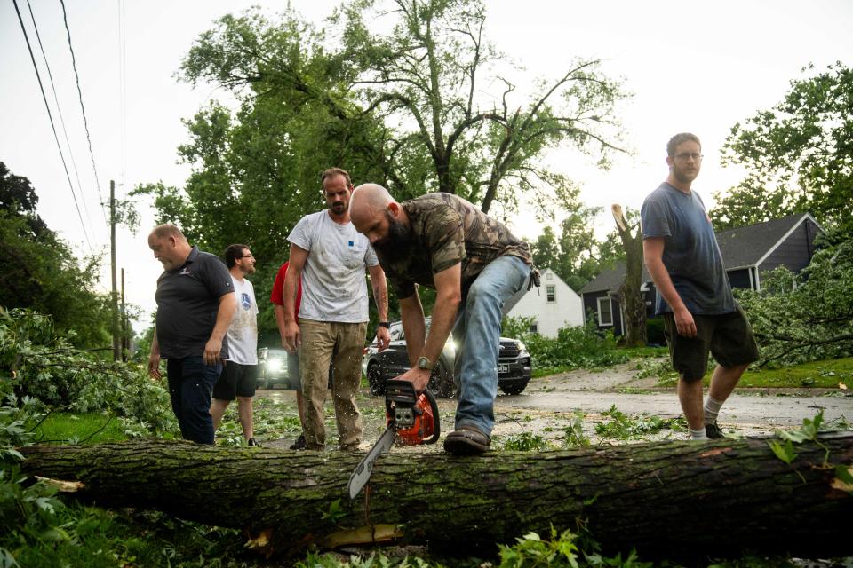 Residents work to clear fallen trees from streets after a tornado swept through the Des Moines metro on Monday, July 15, 2024, in the Merle Hay Neighborhood.