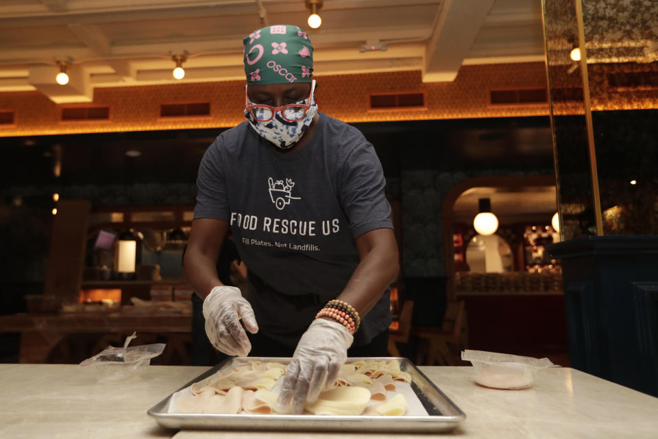 Sharon Holm, a volunteer from Food Rescue US, prepares cold cuts for sandwiches at Marcus Samuelsson's Red Rooster Restaurant during the new coronavirus pandemic, Monday, April 6, 2020, in the Overtown neighborhood of Miami. Samuelsson has partnered with chef Jose Andres' World Central Kitchen to distribute meals to those in need. (AP Photo/Lynne Sladky)