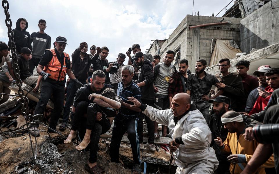 The body of a Palestinian is pulled from the rubble following an Israeli attack on the Nuseirat Refugee Camp in Gaza on Tuesday