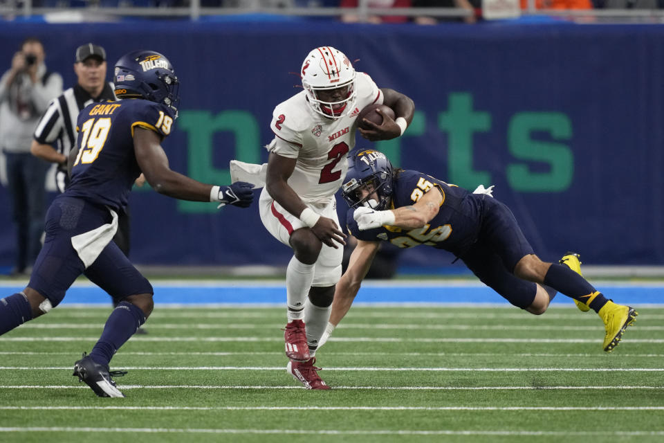 Miami (Ohio) quarterback Aveon Smith (2) rushes past Toledo safety Maxen Hook (25) during the first half of the Mid-American Conference championship NCAA college football game, Saturday, Dec. 2, 2023, in Detroit. (AP Photo/Carlos Osorio)