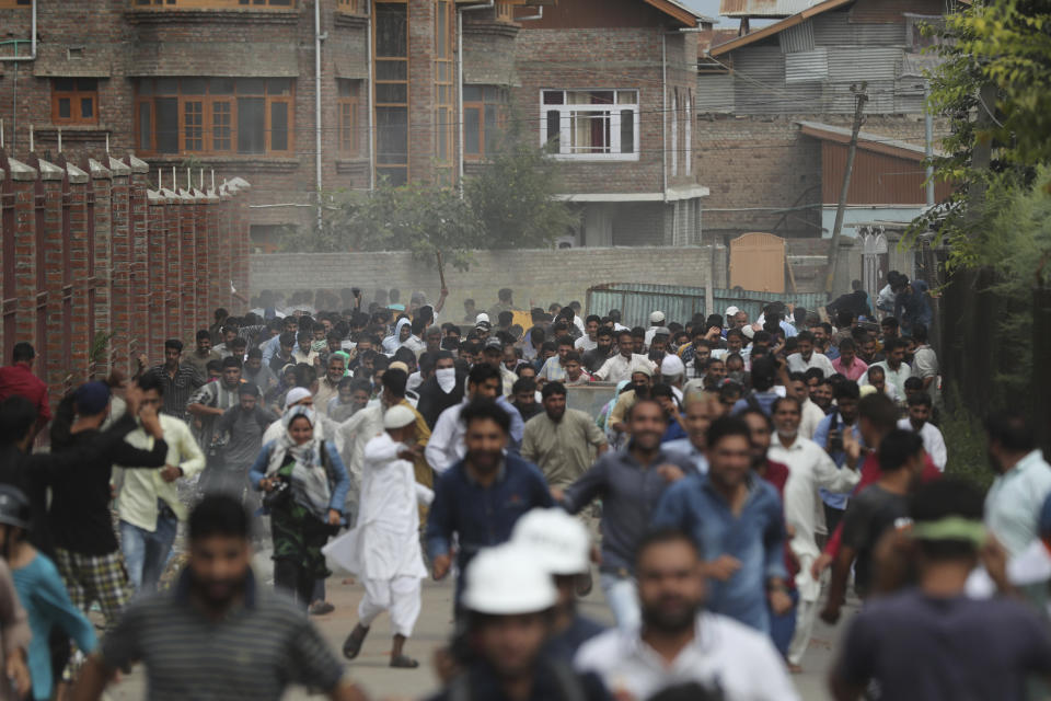 FILE- In this Aug. 30, 2019, file photo, Kashmiris protesting against Indian government stripping the Himalayan state’s semi-autonomous powers run for cover as Indian police use tear gas and pellets to disperse them in Srinagar, Indian controlled Kashmir. A year after India ended disputed Kashmir's semi-autonomous status and downgraded it to a federally governed territory, authorities have begun issuing residency and land ownership rights to outsiders for the first time in almost a century. Many Kashmiris view the move as the beginning of settler colonialism aimed at engineering a demographic change in India’s only Muslim-majority region. (AP Photo/Mukhtar Khan, File)