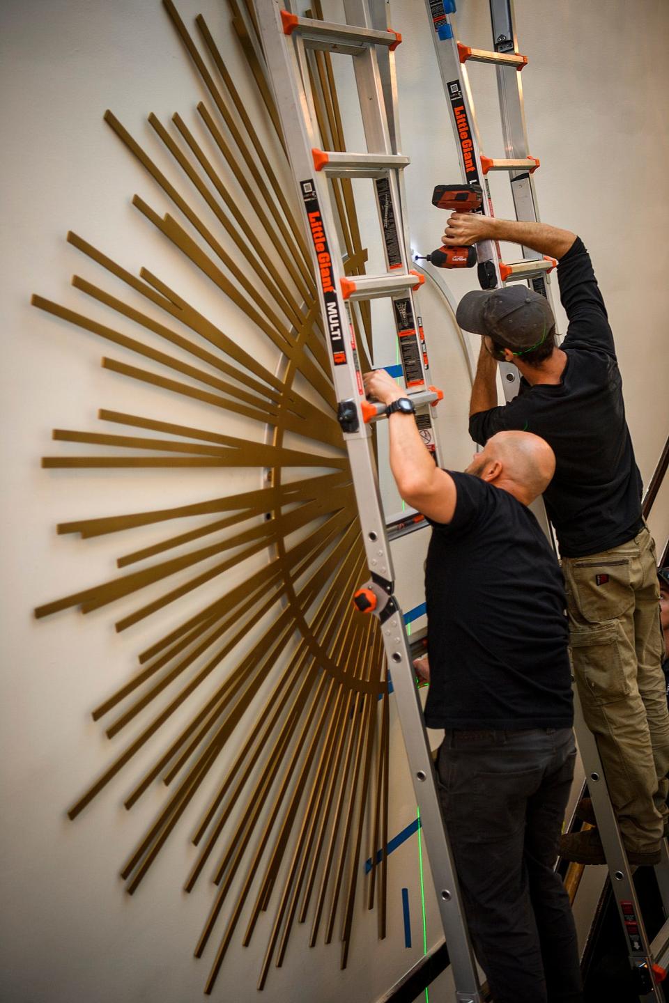 Workers install a custom metal sunburst art piece at the Waldron Arts Center after it was remodeled this year on Wednesday, Oct. 12, 2022.