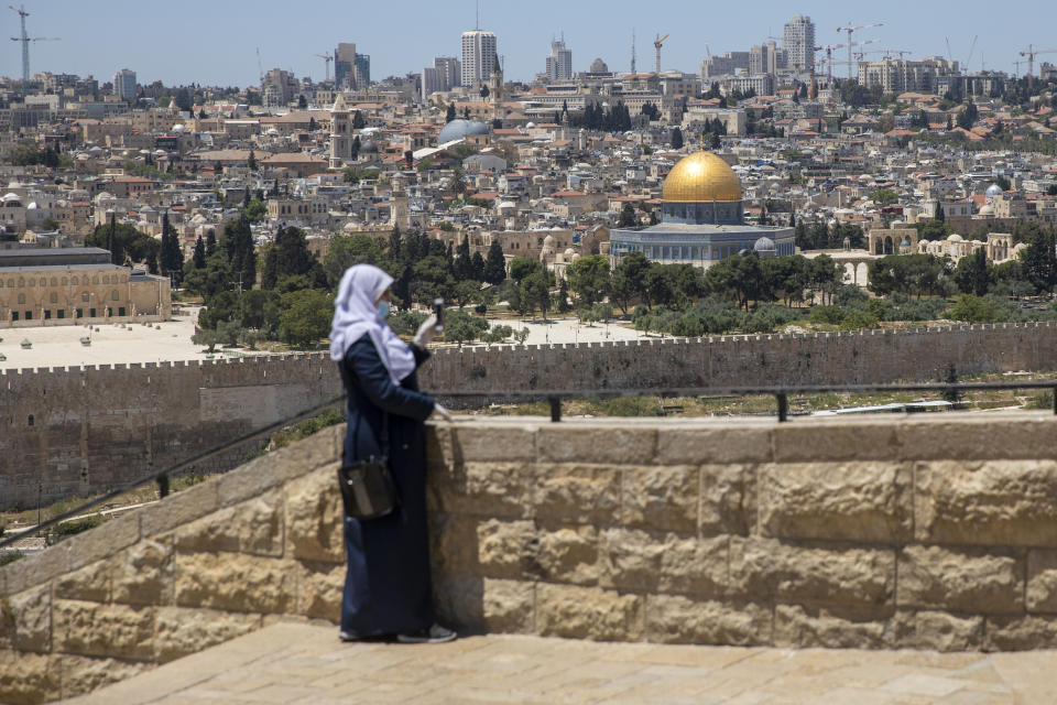 A Muslim woman wears a mask and gloves in east Jerusalem's Mount of Olives, which remains shut to prevent the spread of coronavirus during the holy month of Ramadan, Friday, May 1, 2020. (AP Photo/Ariel Schalit)