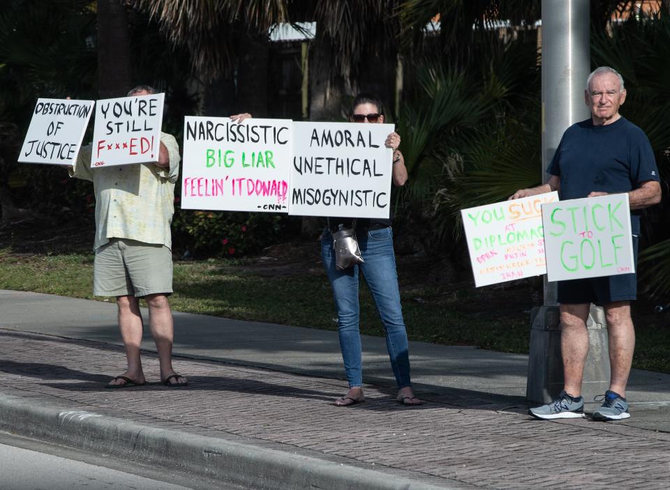 Protesters hold signs as President Donald Trump's motorcade makes its way to the Trump International Golf Club in West Palm Beach, Florida, on April 20, 2019.&nbsp; (Photo: NICHOLAS KAMM via Getty Images)