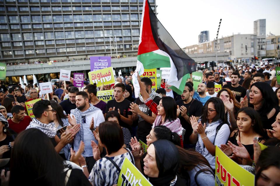 Israeli Arabs hold a Palestinian flag during a protest against the Jewish nation bill in Tel Aviv, Israel, Saturday, Aug. 11, 2018. The recently passed law that enshrines Israel's Jewish character and downgrades the standing of Arabic from an official to a "special" language. (AP Photo/Ariel Schalit)