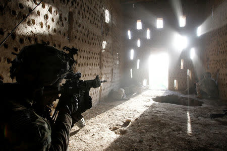 FILE PHOTO: U.S. soldier Nicholas Dickhut from 5-20 infantry Regiment attached to 82nd Airborne points his rifle at a doorway after coming under fire by the Taliban while on patrol in Zharay district in Kandahar province, southern Afghanistan, April 26, 2012. REUTERS/Baz Ratner