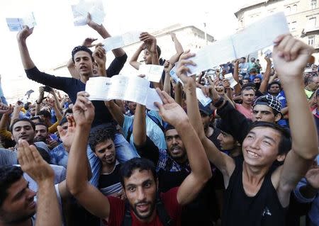 Migrants wave their train tickets outside the main Eastern Railway station in Budapest, Hungary, September 1, 2015. REUTERS/Laszlo Balogh