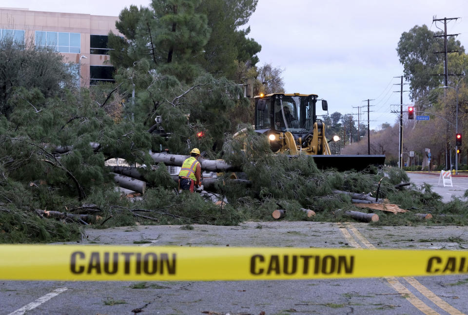 Workers remove a tree that fell across Burbank Blvd. at Canoga Ave. in Woodland Hills, Calif., following a night of steady rain, on Thursday, December 26, 2019. (Dean Musgrove/The Orange County Register via AP)