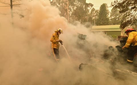 Firefighters hose down a burning woodpile during a bushfire in Werombi, 50km south west of Sydney, Australia, 06 December 2019 - Credit: REX