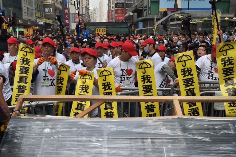 Workers wearing red caps and t-shirts reading "I Love Hong Kong" dismantle barricades built by pro-democracy activists as bailiffs and police continue their clearance of a protest site in the Mongkok district of Hong Kong, on November 26, 2014