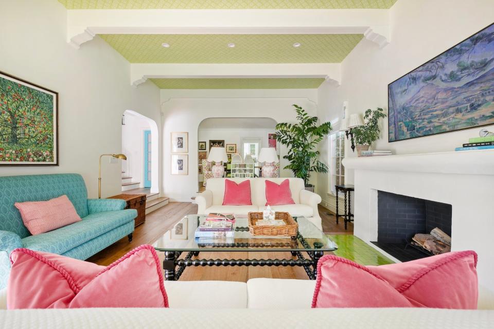 A living room with a green ceiling and a white fireplace.