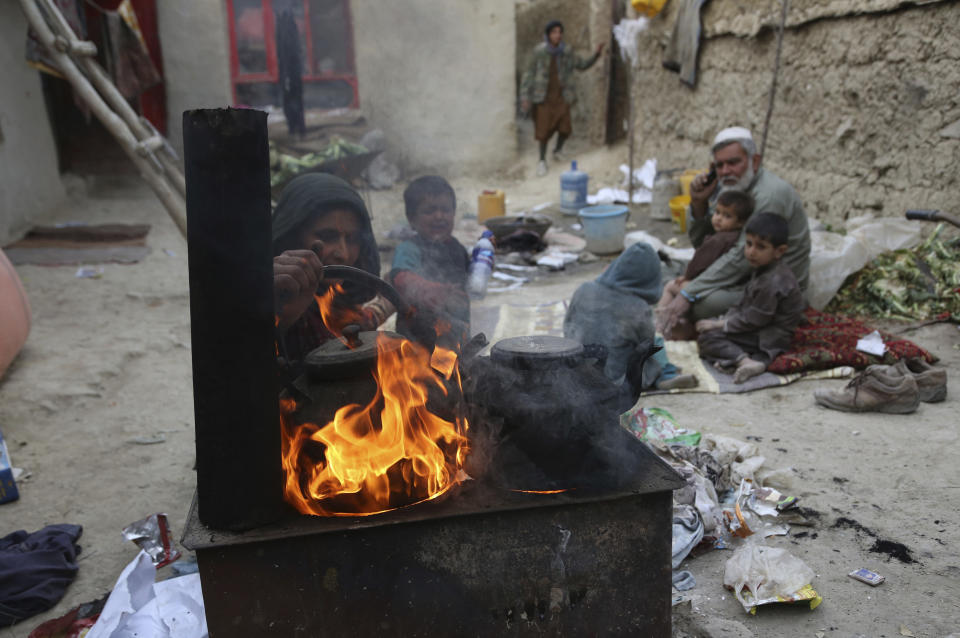 In this Oct. 29, 2019 photo, Yousuf, who fled with his family from his home in eastern Afghanistan eight years ago to escape the war, sits with children while his wife burns plastic as she makes tea, in Kabul, Afghanistan. In the capital, Kabul, five of his children died, not from violence or bombings, but from air pollution, worsened by bitter cold and poverty. (AP Photo/Rahmat Gul)