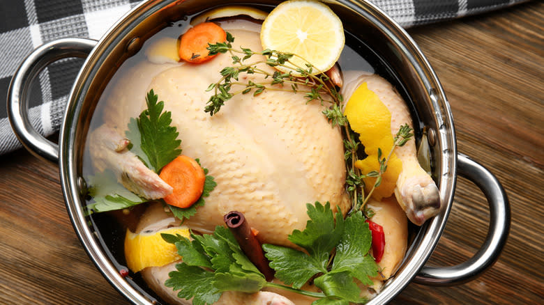 Chicken in pot filled with liquid and herbs