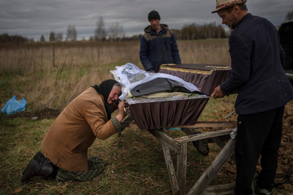 On the outskirts of Kyiv, Ukraine, on April 16, 2022, Nadiya Trubchaninova, 70, cries while holding the coffin of her son Vadym, 48, who was killed by Russian soldiers the prior month.