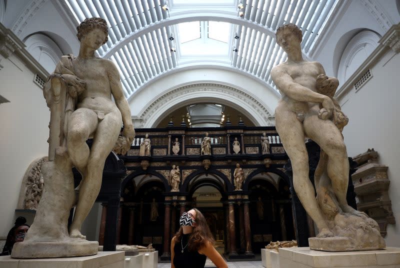 A Victoria & Albert (V&A) Museum gallery assistant poses for members of the media in front of the Apollo and Zephyr sculptures by Pietro Francavilla during preparations to reopen the museum, in London