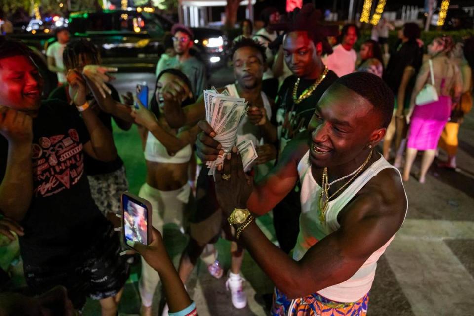 A man flashes cash while recording a video on Ocean Drive during spring break on Friday, March 15, 2024, in Miami Beach. 