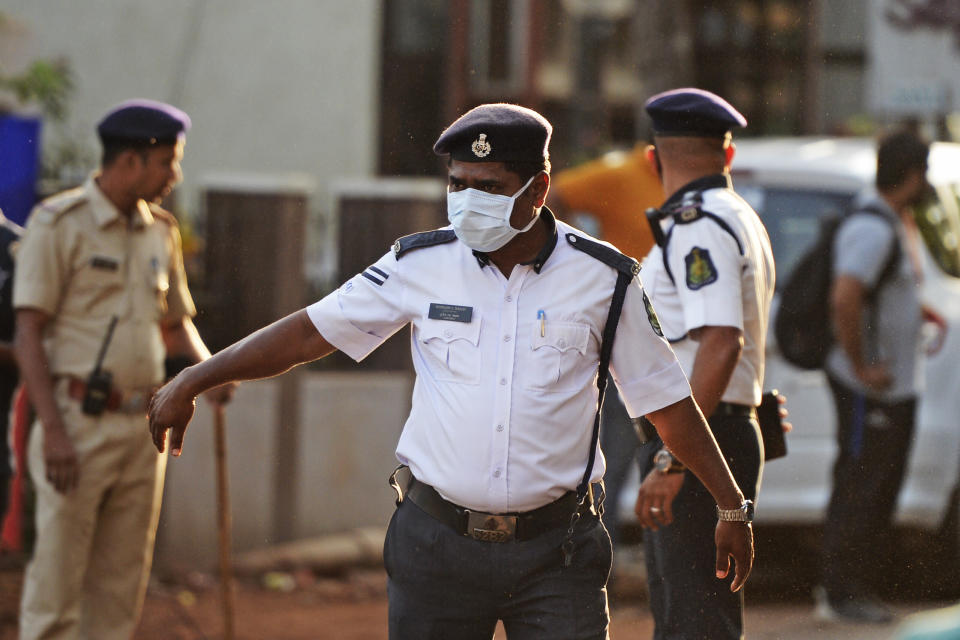 Security personnel wearing facemasks amid concerns over the spread of the COVID-19 novel coronavirus, stand guard outside the Jawaharlal Nehru football stadium. Source: Getty Images
