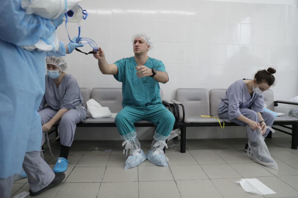 In this photo taken on Friday, May 15, 2020, Dr. Osman Osmanov, center, puts on protective gear before his shift at an intensive care unit of the Filatov City Clinical Hospital in Moscow, Russia. Moscow accounts for about half of all of Russia's coronavirus cases, a deluge that strains the city's hospitals and has forced Osmanov to to work every day for the past two months, sometimes for 24 hours in a row. (AP Photo/Pavel Golovkin)