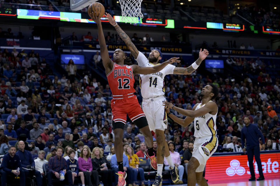 Chicago Bulls guard Ayo Dosunmu (12) shoots against New Orleans Pelicans forward Brandon Ingram (14) during the first half of an NBA basketball game in New Orleans, Sunday, Feb. 25, 2024. (AP Photo/Matthew Hinton)