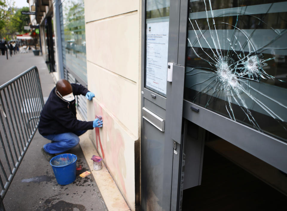 A worker removes a graffiti outside French far-right presidential candidate Marine Le Pen's campaign headquarters, Thursday April 13, 2017 in Paris. The Paris fire department says no one was injured in the incident overnight and the blaze was quickly extinguished. The device hit an insurance office on the ground floor where Le Pen's campaign is based. (AP Photo/Francois Mori)