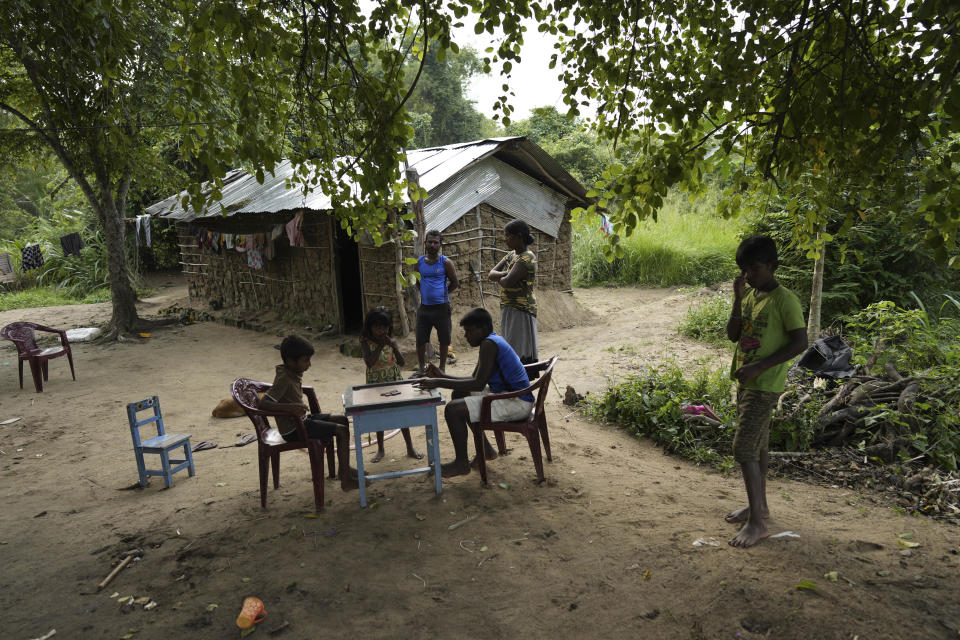 Ranawaka Bandarage Malkanthi, center, and her husband Madushanka Kumara, right, watch their children pass time playing carom outside their house in Mahadamana village in Dimbulagala, about 200 kilometres northeast of Colombo, Sri Lanka, Sunday, Dec. 11, 2022. Due to Sri Lanka's current economic crisis families across the nation have been forced to cut back on food and other vital items because of shortages of money and high inflation. Many families say that they can barely manage one or two meals a day. (AP Photo/Eranga Jayawardena)