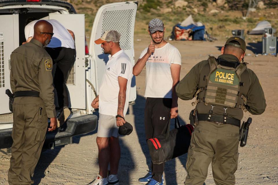 Border Patrol agents load men into the back of a van.