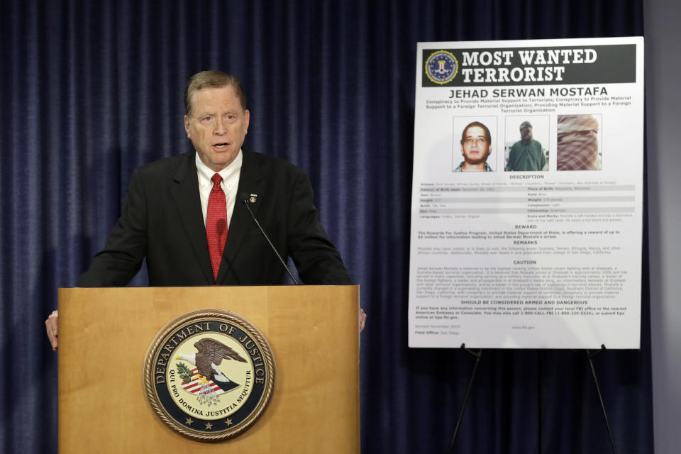 U.S Attorney Robert Brewer speaks in front of an FBI poster depicting Jehad Serwan Mostafa during a news conference Monday, Dec. 2, 2019, in San Diego. The U.S. attorney's office in San Diego says the 37-year-old U.S. citizen who is on the FBI's Most Wanted Terrorist List is facing a new indictment. (AP Photo/Gregory Bull)